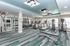 Modern fitness center with cardio machines, weight racks, and chic lighting, offering a bright and spacious workout environment.