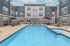 Chic apartment complex showcasing a sparkling outdoor pool, surrounded by modern lounge chairs and stylish architecture under a bright blue sky.