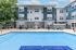 Modern apartment building with a refreshing pool, surrounded by stylish outdoor seating and lush greenery.