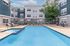 Modern apartment complex with a beautifully maintained pool area, surrounded by comfortable lounge chairs and seating, perfect for relaxation.