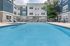 Luxury apartment complex with a serene outdoor pool area, surrounded by stylish lounge chairs and lush greenery.