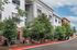 Charming apartment exterior with modern architecture, surrounded by lush greenery and a clear sky backdrop.