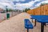 Inviting outdoor area with blue picnic tables and a pet-friendly zone, conveniently located near parking and residential buildings.