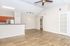 Spacious open-concept living area with elegant wood flooring, modern kitchen, and ceiling fan, perfect for entertaining.