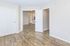 Bright modern apartment with elegant hardwood floors and open double doors leading to a spacious living area.