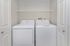 Modern laundry room featuring a sleek washer and dryer set with ample shelving space.