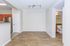 Inviting living space with elegant wooden flooring, modern track lighting, and a glimpse into the kitchen with sleek stainless steel appliances.