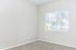Light-filled room featuring soft beige walls, plush carpet, and a window with white blinds offering a serene view.