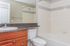 Modern bathroom with elegant wooden cabinetry, pristine white bath, and sleek countertop design.
