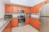 Modern kitchen with warm wood cabinetry, stainless steel appliances, and elegant granite countertops, perfect for culinary enthusiasts.
