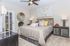 Inviting bedroom with elegant decor, featuring a cozy bed, stylish pillows, chic wall art, and warm lighting.