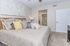 Inviting bedroom with plush pillows, elegant gray and yellow bedding, and a cozy carpet, seamlessly leading to a modern bathroom.