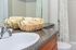 Inviting bathroom with elegant granite countertop, plush towels in a woven basket, and stylish shower curtain.