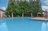 Inviting outdoor pool surrounded by lush greenery and stylish brick columns, offering a serene and relaxing environment.