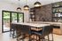 Luxurious kitchen featuring a chic marble island, elegant black pendant lights, and modern open shelves, seamlessly opening to a spacious patio.