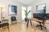 Modern, sunlit office space with sleek black chairs, abstract artwork, and dual monitors on a sturdy desk.
