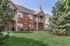 Charming brick apartment complex with a lush green lawn, featuring a cozy balcony and inviting outdoor seating area.