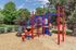 Vibrant playground with colorful equipment surrounded by lush greenery, promoting family-friendly community living.