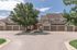 Charming suburban townhouse with a spacious garage, framed by lush greenery and vibrant trees on a sunny day.