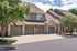 Charming townhouse with stone accents, multiple garages, and lush greenery located in a serene neighborhood.