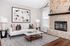 Chic living room with a stylish stone fireplace, cozy white sofa, and elegant decor, perfect for modern relaxation.