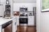 Modern kitchen with sleek stainless steel appliances, elegant white cabinetry, and a chic wood floor, offering a stylish and functional cooking space.