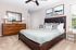 Inviting bedroom featuring a plush bed, stylish wooden dresser with twin lamps, and contemporary framed artwork.