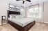 Inviting bedroom with elegant decor, featuring a luxurious bed, plush carpet, modern artwork, and ample natural light from large windows.