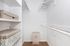 Spacious and organized walk-in closet with built-in shelving, providing ample storage solutions for a modern apartment.