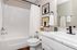 Modern bathroom featuring elegant white fixtures, marble countertop, and stylish artwork for a touch of sophistication.