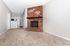 Inviting living space with a charming brick fireplace and cozy carpet flooring, seamlessly leading to a modern kitchen with sleek stainless steel appliances.