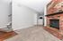 Inviting living space featuring a cozy brick fireplace, plush carpet, and a modern staircase leading to an updated kitchen in a beautifully designed apartment.