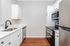 Contemporary kitchen with sleek stainless steel appliances, elegant white cabinetry, and rich wooden flooring.