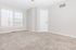 Bright and spacious room with plush carpeting, large windows, and modern neutral tones, perfect for cozy living.