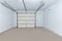 Spacious single-car garage with pristine white walls, high ceiling, and convenient side door access.