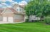 Charming suburban home with a double garage, brick facade, and lush green lawn, complemented by a mature tree.