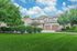 Charming apartment complex with lush green landscaping, vibrant shrubbery, and a clean, elegant facade under a bright blue sky.
