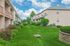 Charming apartment complex with lush green landscaping and picturesque balconies under a bright blue sky.