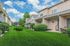 Charming row of modern townhouses with pristine landscaping and vibrant green lawns under a bright blue sky.