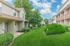 Charming suburban apartment complex with manicured lawns, lush greenery, and a tranquil setting under a bright blue sky.