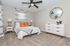Inviting bedroom with contemporary decor featuring a comfortable bed, stylish orange accents, and elegant furnishings under a modern ceiling fan.