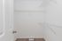Spacious walk-in closet with sleek white shelving and plush carpet flooring.