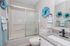 Modern bathroom with elegant granite countertop, stylish glass shower door, and artistic blue wall accents.