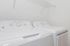 Bright and efficient laundry room equipped with modern washer and dryer, featuring a convenient overhead storage shelf.