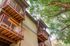 Charming apartment building with vibrant red balconies nestled among lush green trees, creating a serene and inviting atmosphere.