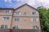 Charming apartment exterior showcasing modern windows and a gabled roof, set against a clear blue sky and lush green trees.