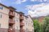 Modern apartment building with charming balconies set against a picturesque mountain backdrop, under a vibrant blue sky.