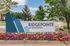 Inviting entrance sign of Ridgepointe at Gleneagle surrounded by vibrant flowers and lush greenery.