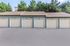 Charming row of five residential garages with a clean facade and lush greenery backdrop.