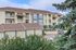 Charming multi-story apartment building with balconies, surrounded by lush greenery and convenient garages.